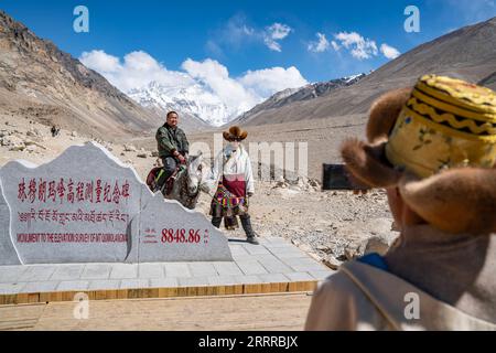 230521 -- XIGAZE, 21 maggio 2023 -- i turisti si pongono per delle foto accanto al monumento all'elevazione del Monte Qomolangma nella città di Zhaxizom della contea di Tingri nella città di Xigaze, regione autonoma del Tibet della Cina sud-occidentale, 20 maggio 2023. Il campo base del Monte Qomolangma per i turisti è costellato di hotel in tenda che accolgono viaggiatori da lontano. Le tende sono realizzate in pelliccia di yak nero, una scena unica ai piedi della montagna. Dainzin, un locale di 27 anni, gestisce un hotel in tenda al campo base da quasi un decennio. Egli è un testimone della crescita del turismo in forte espansione qui. Accesso all'acqua corrente, elettrici Foto Stock