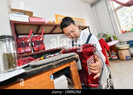 230527 -- TIANJIN, 27 maggio 2023 -- Un operaio mette una fisarmonica a Tianjin Yingwu Musical Instrument Co., Ltd. A Zhongwang Town of Jinghai District, North China S Tianjin, 25 maggio 2023. Tianjin Yingwu Musical Instrument Co., Ltd. È un'azienda con 71 anni di storia nella produzione di fisarmoniche. Negli anni '1950, il suo predecessore Tianjin Musical Instrument Factory produsse la prima fisarmonica in nuova Cina, con un marchio chiamato Yingwu . Da allora, le fisarmoniche Yingwu prodotte qui divennero famose in patria e all'estero. Negli ultimi anni, l'impresa ha portato avanti l'innovazione tecnologica e.. Foto Stock