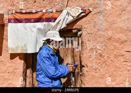 230528 -- ZANDA, 28 maggio 2023 -- Rigzin Wangzhab sblocca la porta di una grotta nella contea di Zanda della prefettura di Ngari, regione autonoma Tibet della Cina sud-occidentale, 26 maggio 2023. Nascosto tra le colline di arenaria nel remoto Tibet occidentale, un tratto di caverne a forma di nido d'ape è ben oltre la portata della maggior parte dei viaggiatori. Conosciute come le grotte di Donggar e Piyang, le caverne di 1.000 anni nella prefettura di Ngari della regione autonoma del Tibet ospitano una delle più grandi collezioni al mondo di murales buddisti tibetani. Rigzin Wangzhab, 75 anni, è stato a guardia del sito per più di 20 anni. Quando ero molto giovane, lo ero Foto Stock