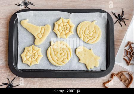 Preparazione di biscotti per le feste da cuocere in forno. Biscotti di Halloween pronti da cuocere a forma di zucche e fantasmi Foto Stock