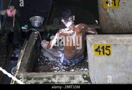 Una persona si lava con il sapone in un pennarello di cemento all'aperto al Mahalakshmi Dhobi Ghat, dove la gente lava i vestiti a mano, che si dice essere il più grande locale di lavanderia all'aperto del mondo a Mumbai in India Foto Stock