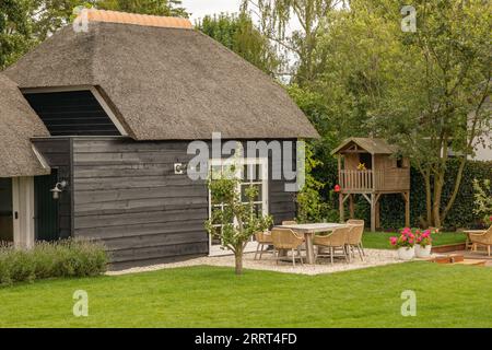 casa in legno con tetto in paglia e giardino ben tenuto Foto Stock