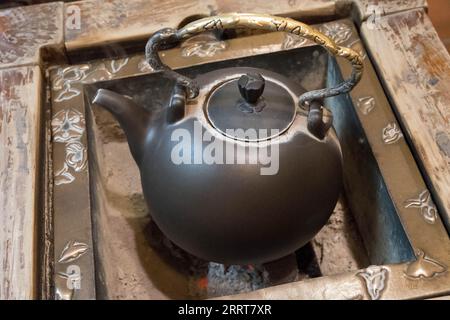 Bollitore cinese tradizionale in metallo su baccelli che bollono l'acqua per il tè. Riprese 4K di alta qualità. Foto Stock