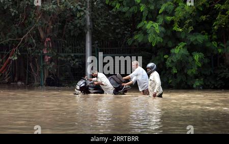 230714 -- NUOVA DELHI, 14 luglio 2023 -- le persone si sono imbattute in una strada allagata a nuova Delhi, India, 13 luglio 2023. Il livello dell'acqua del fiume Yamuna, che passa attraverso nuova Delhi, continua a rimanere al di sopra del segno di pericolo, ponendo paura delle inondazioni, in particolare nelle zone basse della città. Str/Xinhua INDIA-NUOVA DELHI-ALLUVIONE JavedxDar PUBLICATIONxNOTxINxCHN Foto Stock