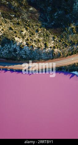 Una vista aerea di un corpo d'acqua con una tonalità rosa, caratterizzata da una lunga strada che lo attraversa. Foto Stock