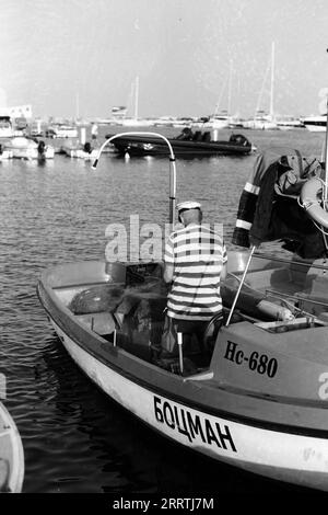Fotografia di un pescatore tradizionale in una piccola barca al porto di Sveti Vlas, ripresa su pellicola in bianco e nero Foto Stock