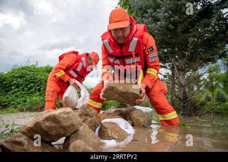 230805 -- HARBIN, 5 agosto 2023 -- i vigili del fuoco trasferiscono rocce per bloccare le inondazioni vicino al villaggio di Dawan del distretto di Dong An, Mudanjiang, provincia di Heilongjiang della Cina nordorientale, 5 agosto 2023. Innescato da piogge torrenziali nella città di Mudanjiang e nella capitale provinciale Harbin, i livelli dell'acqua di alcuni fiumi hanno superato il livello dell'acqua di avvertimento. Squadre di soccorso di emergenza, tra cui vigili del fuoco locali e vigili del fuoco forestale, sono stati inviati per aiutare con il lavoro di soccorso e soccorso. Le pattuglie di 24 ore sui terrapieni sono state condotte per controllare i rischi, e le inondazioni hanno colpito i residenti ha Foto Stock