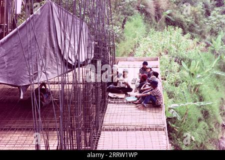 Un gruppo di costruttori indonesiani maschi che si riposano in un cantiere Foto Stock