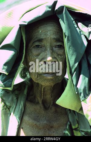 Vecchia signora balinese che indossa una copertura per proteggersi dal sole ardente Foto Stock