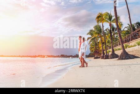 Coppia innamorata che abbraccia la spiaggia sabbiosa esotica mentre si cammina di sera sul mare di Trou-aux-Biches sull'isola di Mauritius godendo il tramonto. Persone relatio Foto Stock