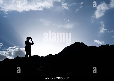 230822 -- HOHHOT, 22 agosto 2023 -- Dong Haining usa un binocolo per osservare una sezione della grande Muraglia nel nord della Cina, 20 agosto 2023. Dong Haining, 42 anni, è stato protettore della grande Muraglia dal 2016. Nel corso degli anni, ha pattugliato una sezione della grande Muraglia situata nelle montagne Helan mentre ripuliva rifiuti e erbacce, ricordando ai turisti di preservare il muro. CHINA-HELAN MOUNTAINS-GREAT WALL-PROTECTION CN LIUXJINHAI PUBLICATIONXNOTXINXCHN Foto Stock