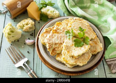 Cotolette vegetariane fritte o pancake. Frittelle di cavolfiore con formaggio su un tavolo da cucina rustico. Foto Stock