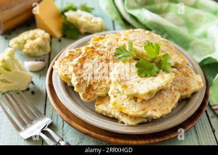 Frittelle di cavolfiore con formaggio su un tavolo da cucina rustico. Cotolette vegetariane fritte o pancake. Foto Stock