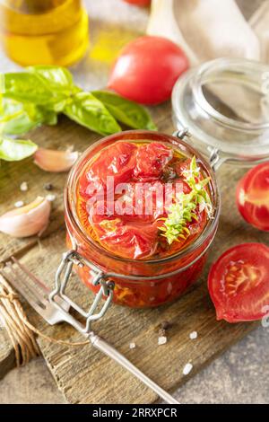 Cibo fermentato sano fatto in casa. Pomodori secchi in vaso con spezie ed erbe aromatiche. Economia domestica, conservazione del raccolto autunnale. Foto Stock