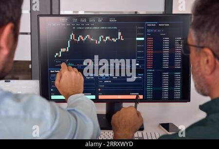 Due trader che discutono dei dati finanziari del mercato cripto durante la riunione. Primo piano Foto Stock