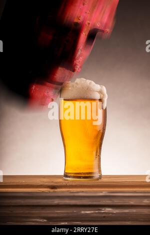 Birra con robot ai alla scoperta di una pinta di birra su un tavolo di legno in un pub Foto Stock