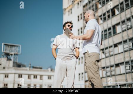 Architetti e ingegneri collaborano all'esterno, analizzando progetti e schizzi per un progetto di edificio moderno. Lavoro di squadra di successo per il design urbano. Foto Stock