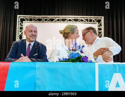 09 settembre 2023, Assia, Gelnhausen: Robert Lambrou (l-r, AfD), presidente dello stato AfD/candidato leader per le elezioni statali, Alice Weidel (AfD), presidente del partito federale, e Tino Chrupalla (AfD), presidente del partito federale, siedono insieme sul podio. L'Hessian AfD tiene la sua campagna d'avvio per le elezioni statali in Assia nella sala dello sport e della cultura di Meerholz. Diverse associazioni e istituzioni manifestano ai margini dell'evento AfD con lo slogan "siamo di più! - Festival della democrazia e della coesione sociale". Le elezioni in Assia si svolgeranno l'8 ottobre 2023. Foto: Foto Stock