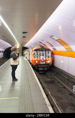 Treno della metropolitana SPT che arriva alla stazione della metropolitana di Glasgow Kinning Park sulla metropolitana di Glasgow con passeggeri in attesa sul binario Foto Stock