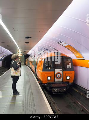 Treno della metropolitana SPT che arriva alla stazione della metropolitana di Glasgow Kinning Park sulla metropolitana di Glasgow con passeggeri in attesa sul binario Foto Stock