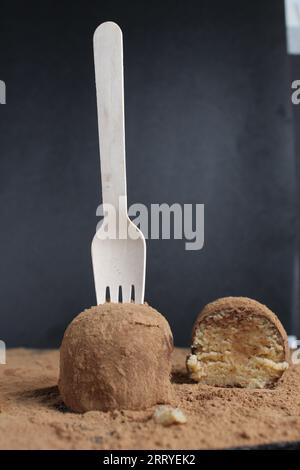 patate rotonde da dessert al cioccolato con una forchetta di legno ecologica su sfondo nero. Dessert salutare Foto Stock