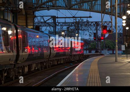 Il treno di pianura Caledonian Sleeper in attesa di partire dalla stazione centrale di Glasgow con un segnale rosso che sfreccia lungo il lato del treno Foto Stock