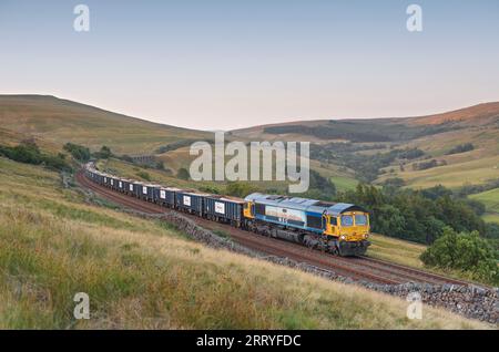 GB Railfreight classe 66 locomotiva diesel che trasporta un treno merci attraverso Dentdale, Cumbria, Regno Unito, sulla scenografica linea ferroviaria di Carlisle Foto Stock