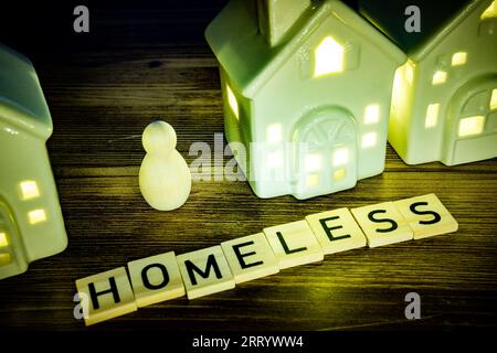 parola senzatetto in lettere di legno su sfondo di legno, una figura di legno senza casa Foto Stock