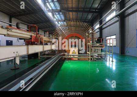 I lavoratori controllano i macchinari per produrre lastre sulla linea di produzione Foto Stock