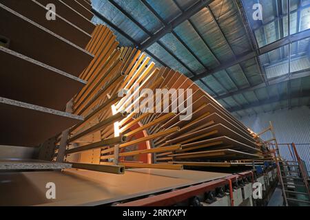 I lavoratori controllano i macchinari per produrre lastre sulla linea di produzione Foto Stock