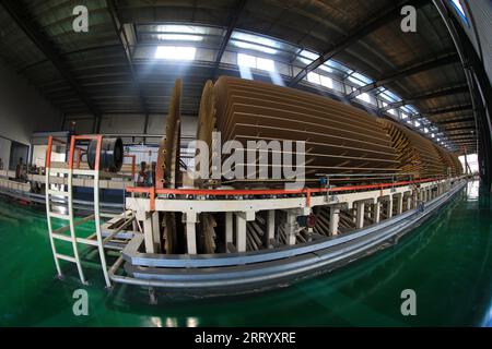 I lavoratori controllano i macchinari per produrre lastre sulla linea di produzione Foto Stock