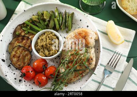 Gustoso pollo, verdure con dragoncello e pesto serviti al tavolo, vista dall'alto Foto Stock