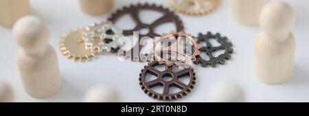 Figure di legno di persone con ingranaggi metallici primo piano. Foto Stock