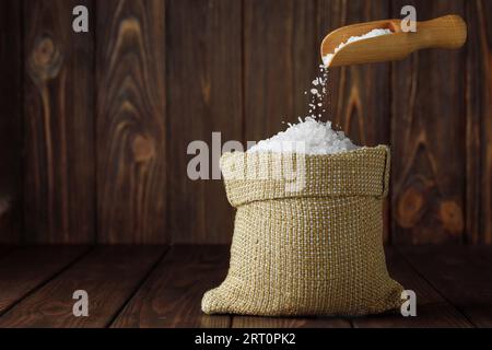 sale marino che cade dalla paletta in sacchetto su un tavolo di legno Foto Stock