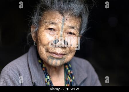 Ritratto di anziana donna tribale di minoranza etnica Apatani indiana con tappi neri in legno e tatuaggi tradizionali per il viso, Arunachal Pradesh, India Foto Stock