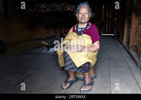 Donna della tribù degli apatani in una casa di un piccolo villaggio vicino a Ziro, con tradizionali tatuaggi facciali e tappi per naso tradizionali, Ziro, India Foto Stock