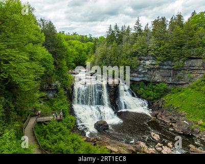 Una splendida cascata che scende lungo una scogliera rocciosa in mezzo a una lussureggiante foresta verde Foto Stock