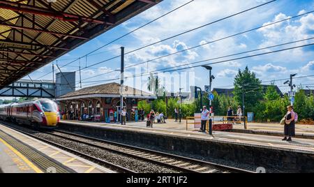 Un treno LNER Azuma passa attraverso la stazione ferroviaria di Grantham ad alta velocità viaggiando verso nord in una giornata estiva sotto un cielo estivo blu Foto Stock