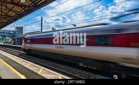 Stazione ferroviaria di Grantham: Passeggeri e viaggiatori che aspettano sulla piattaforma in un giorno d'estate sotto un cielo blu estivo Foto Stock