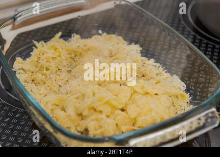 Casseruola di vetro con Spaetzle formaggio, una specialità della germania meridionale fatta di grumi di pasta in piedi sul forno Foto Stock