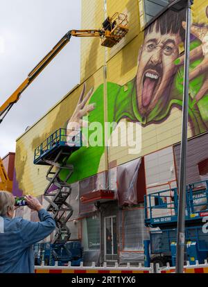 Un murale raffigurante Käärijä dipinto, da piattaforme di lavoro aeree, su una parete dell'ipermercato di Prisma a Tikkurila. Un passante sta scattando una foto. Foto Stock