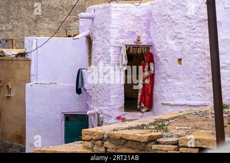 Jaisalemer, India, 5 dicembre 2019: Una donna indiana in abiti colorati in piedi di fronte alla sua casa Foto Stock