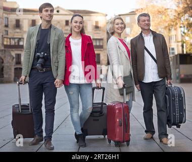 I turisti con valigie e macchina fotografica camminano lungo le strade storiche della città europea Foto Stock