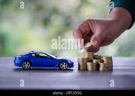 Donna d'affari e mano ravvicinata che tiene moneta su oltre un sacco di soldi di monete impilate assicurazione, prestito e acquisto di auto concetto di finanziamento. acquisto e rata Foto Stock