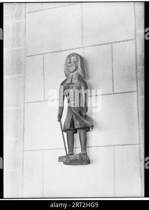 St Albans Cathedral, St Albans, Hertfordshire, luglio 1958. Dettaglio di una figura di legno sul muro sopra una povera scatola nell'ambulatorio sud della chiesa della cattedrale. Foto Stock