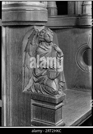 St Albans Cathedral, St Albans, Hertfordshire, luglio 1958. Dettaglio di un intaglio in legno sulla bancarella del coro degli Arcidiaconi nella chiesa della cattedrale, raffigurante un angelo con uno strumento a corde. Foto Stock