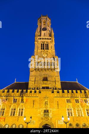 Vista dal basso angolo del campanile di Bruges al crepuscolo con un cielo blu sullo sfondo. Foto Stock