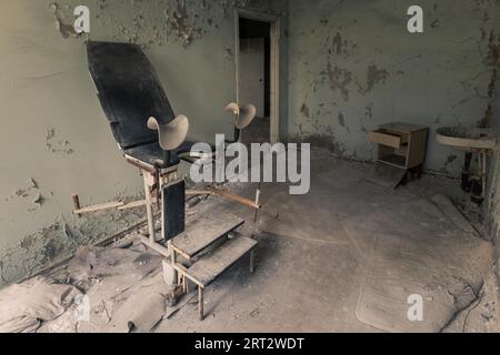 Sedia ginecologica in sala operatoria in ospedale abbandonato a Pripyat, zona di esclusione di Cernobyl Foto Stock