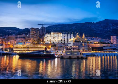 Monaco Monte Carlo skyline a ora blu crepuscolo, luci della città con la riflessione nel Mare Mediterraneo Foto Stock