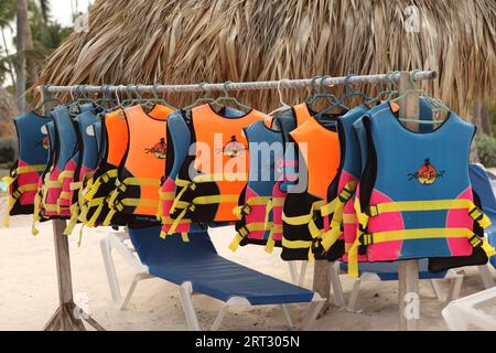 Una collezione di giubbotti di salvataggio Aloha Sports appesi su un rack in una spiaggia caraibica, Repubblica Dominicana, Punta Cana 2023 Foto Stock